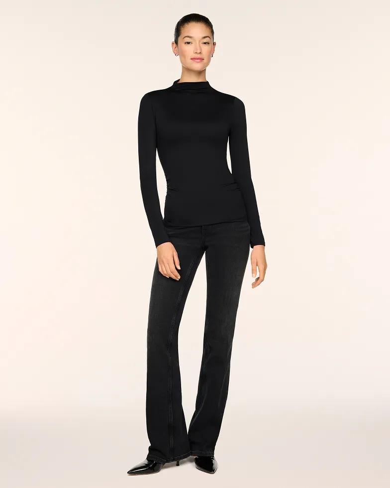 Model wears a black fitted mock-neck long-sleeve top paired with black bootcut jeans and black pointed-toe kitten heels.