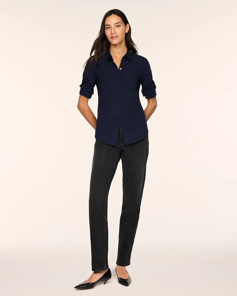 Model wears a navy button-down collared shirt with long rolled sleeves, paired with black straight-leg jeans and black pointed-toe kitten heels.