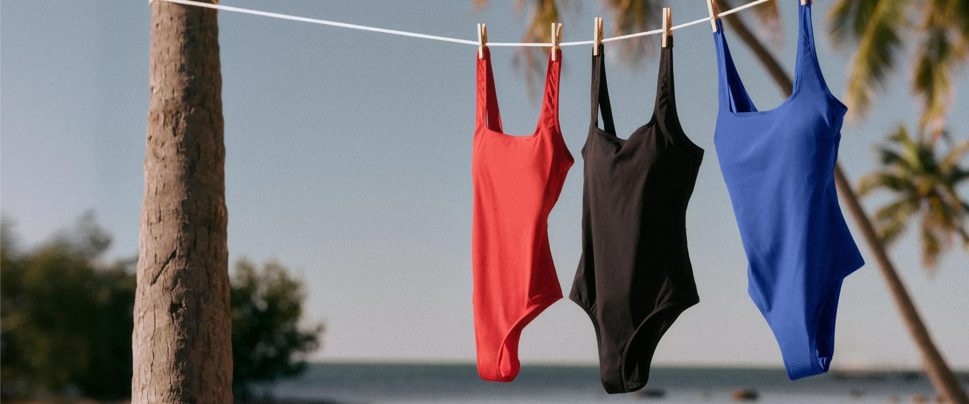 three one piece spanx swimsuits hanging from a clothesline at the beach